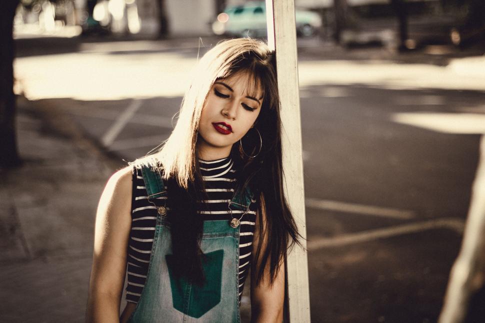 Free Image of Woman Standing Next to Pole With Eyes Closed 