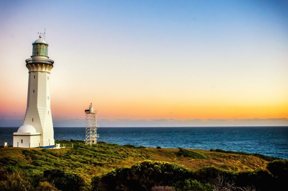 Free Image of White Lighthouse on Lush Green Hillside 