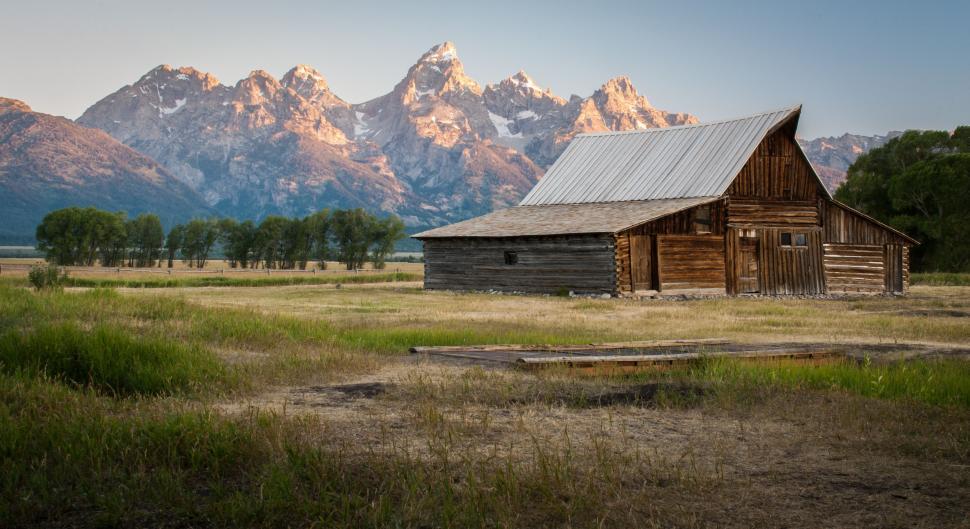 Free Image of Barn in a Field With Mountains in the Background 