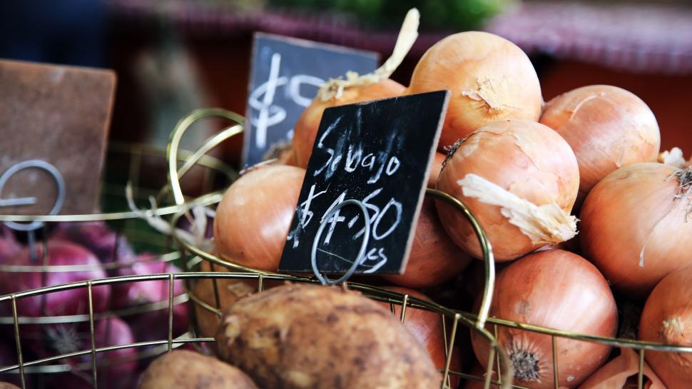 Free Image of A Basket Full of Onions Beside a Sign 
