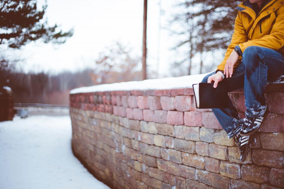 Free Image of Man Sitting on Top of a Brick Wall 