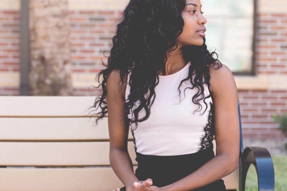 Free Image of Woman Sitting on Bench in Front of Building 