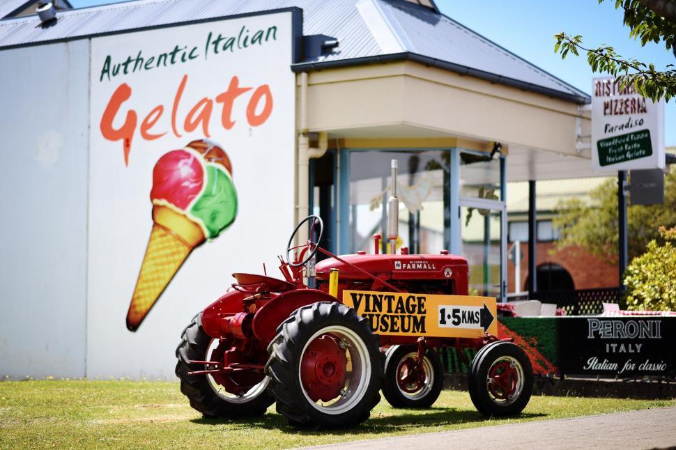 Free Image of Red Tractor Parked in Front of Building 