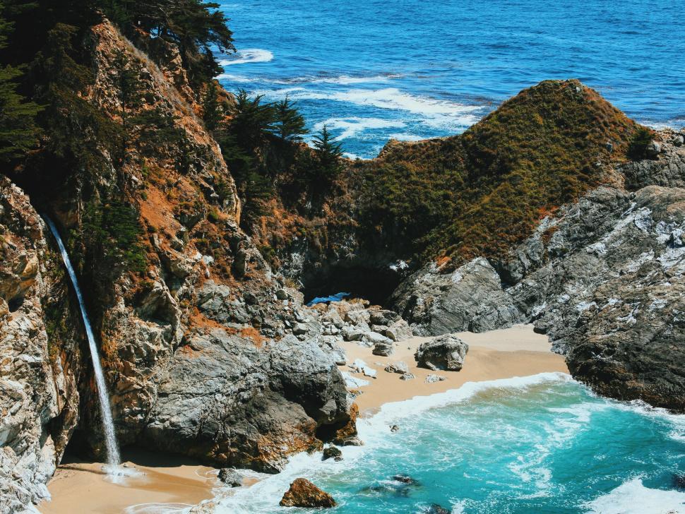 Free Image of Waterfall Flowing From Rocks Into Ocean 