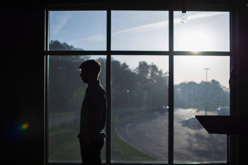 Free Image of Man Standing in Front of Window 