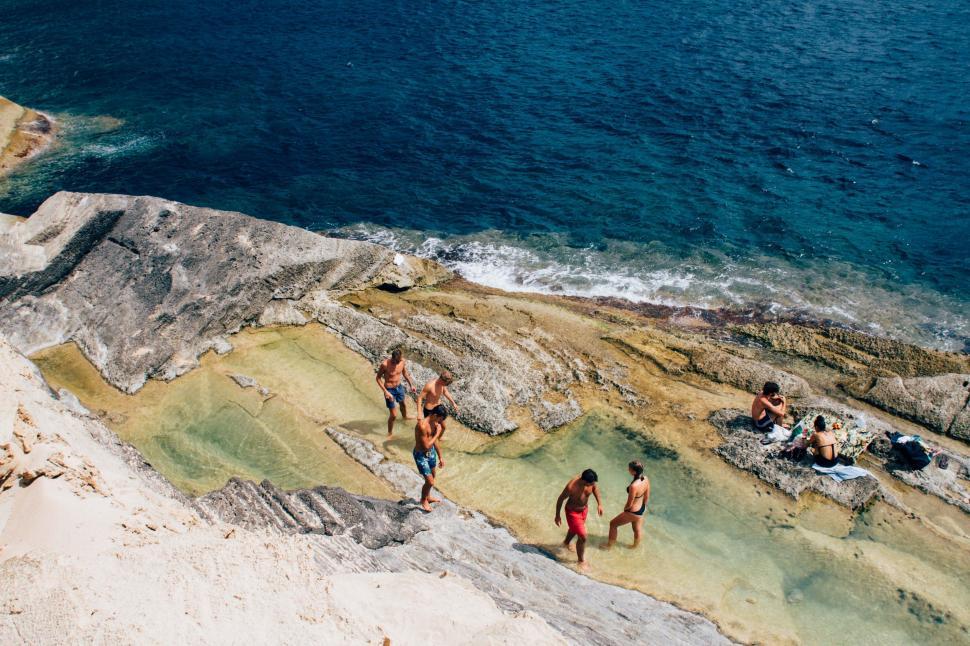 Free Image of Group of People Standing on Cliff by Ocean 