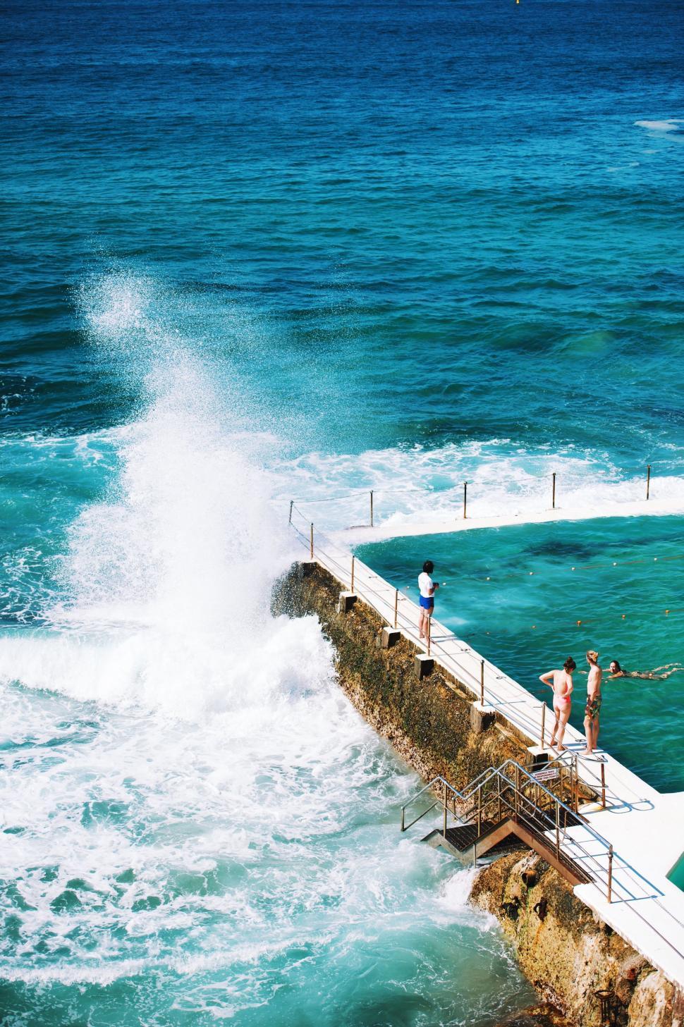 Free Image of Group of People Standing on Top of Pier by the Ocean 