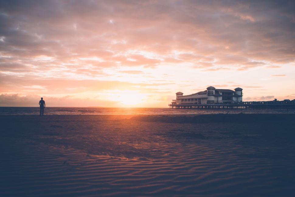 Free Image of Person Standing on Beach at Sunset 
