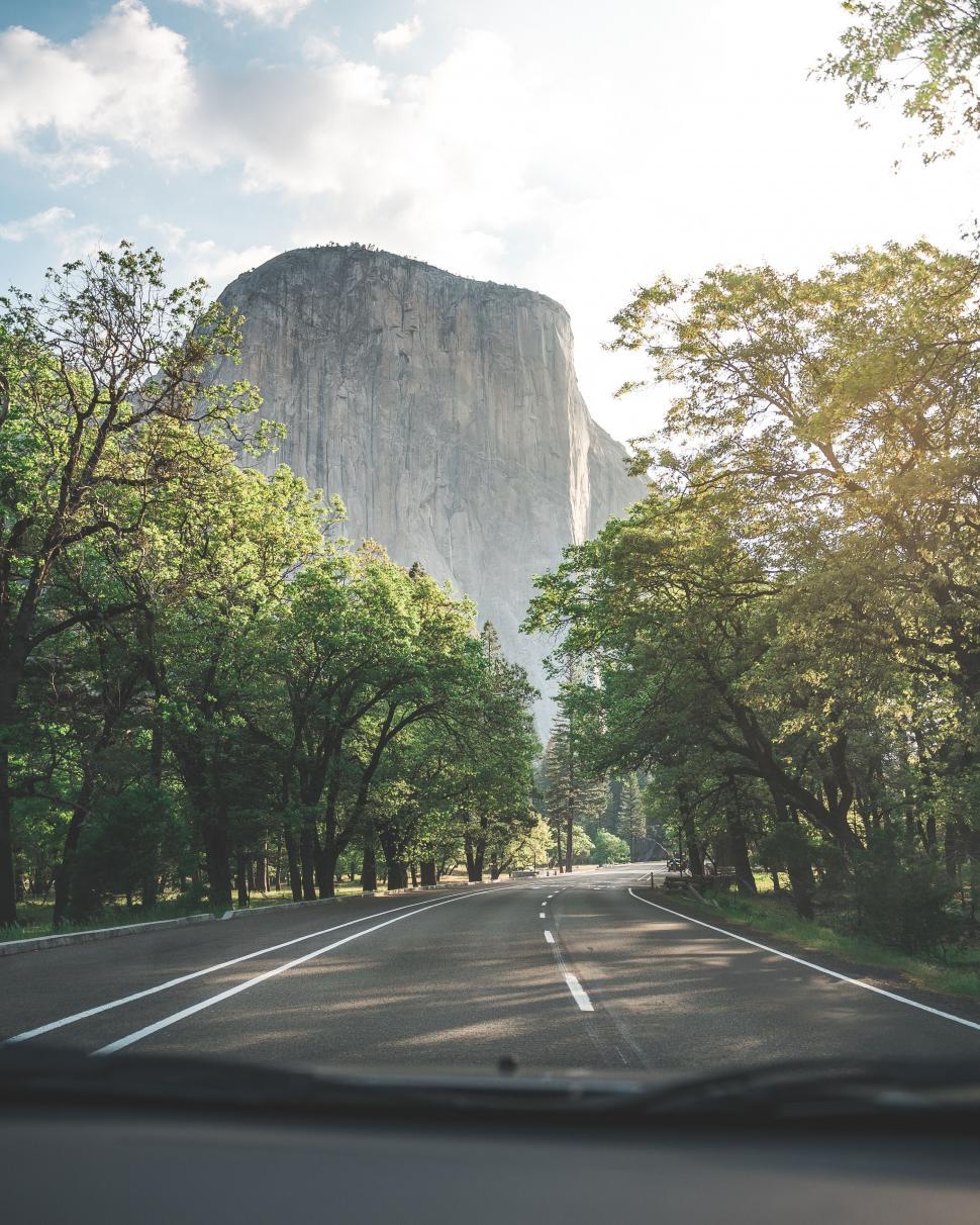 Free Image of Car Driving Along Road Next to Tall Mountain 