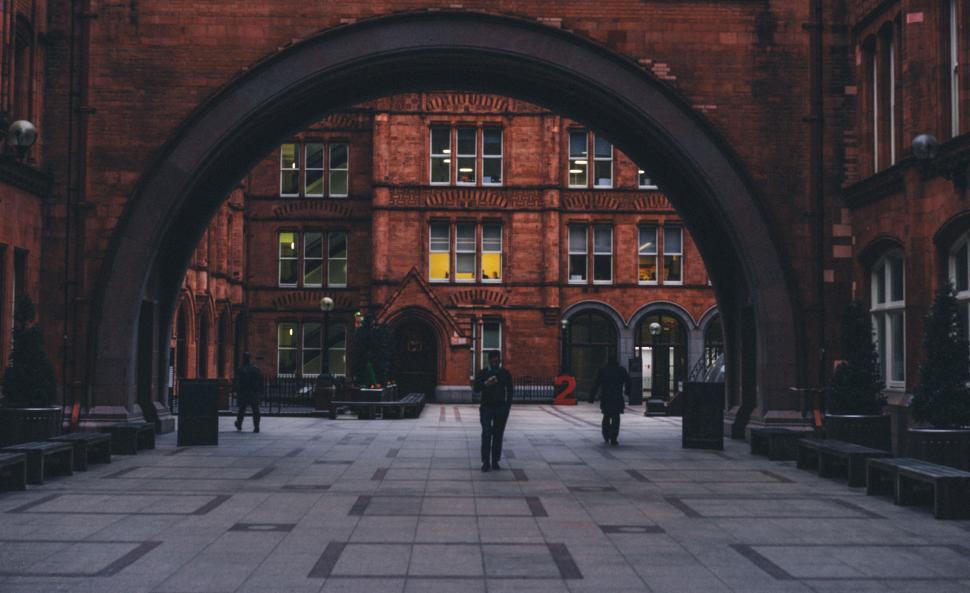 Free Image of Man Walking Through Archway in Brick Building 