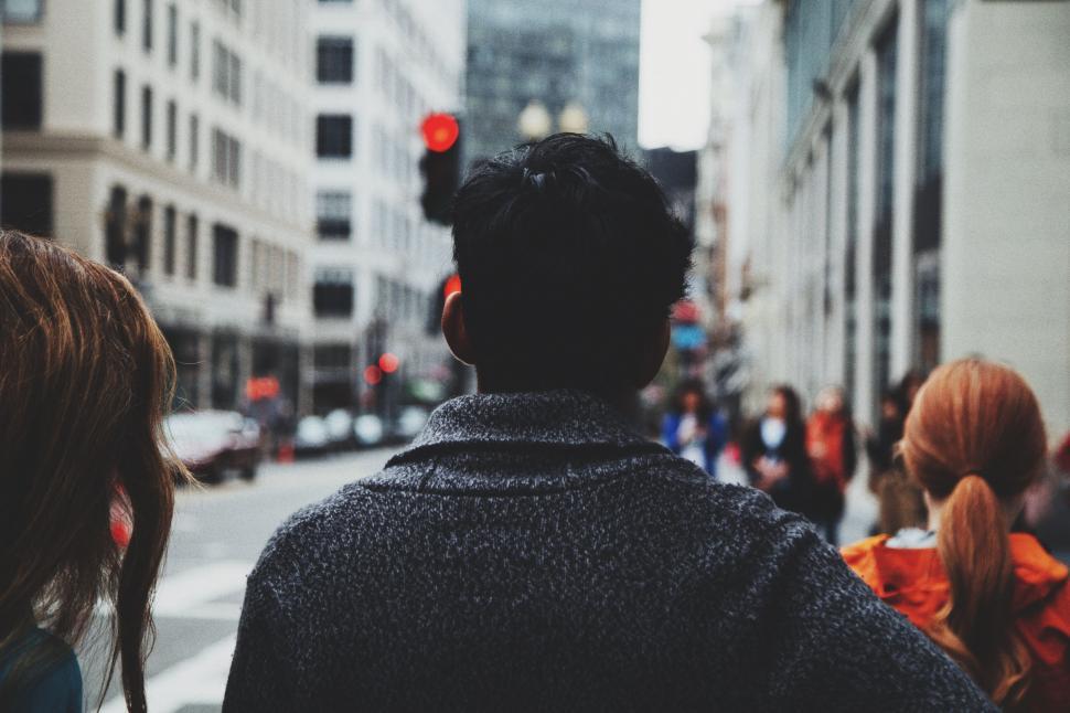Free Image of Group of People Walking Down a Street Next to Tall Buildings 