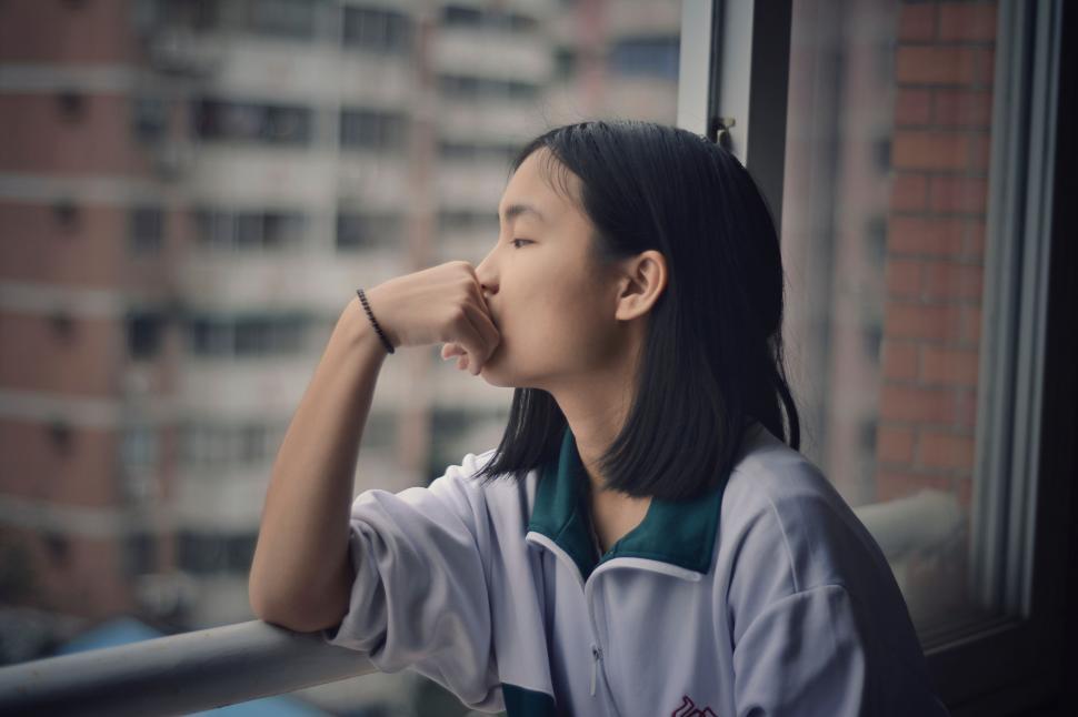 Free Image of Woman Sitting on Window Sill Looking Out Window 