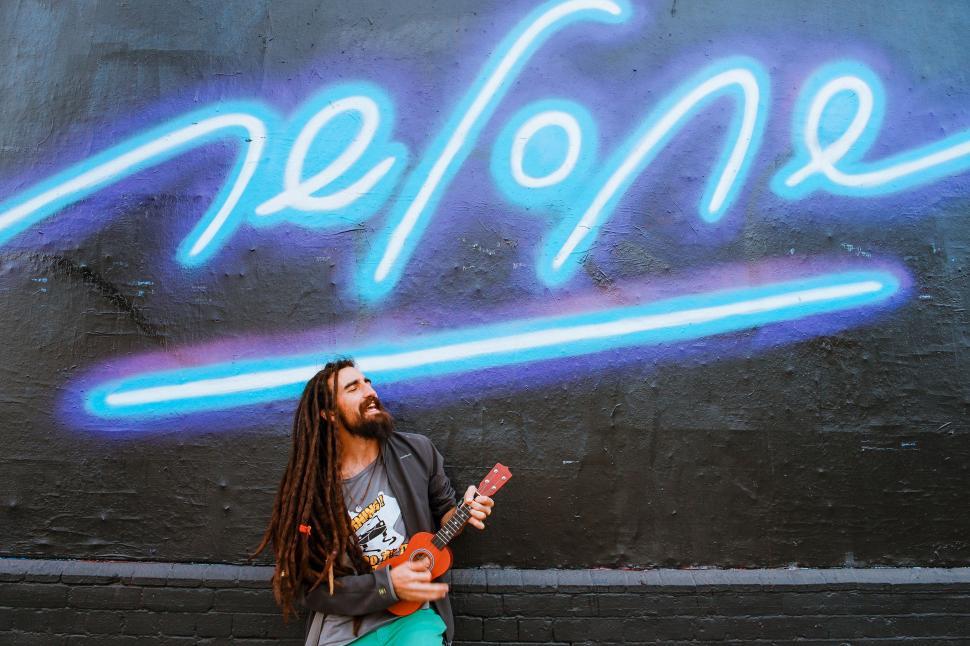 Free Image of Man Standing in Front of Wall With Guitar 