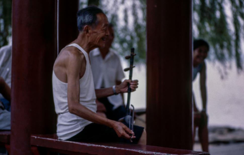 Free Image of Man Sitting on Bench Holding Fishing Pole 