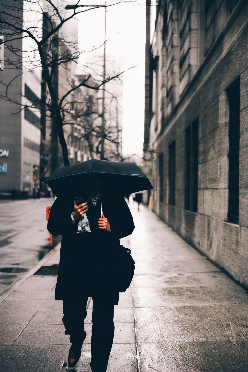 Free Image of Person Walking Down Street Holding Umbrella 