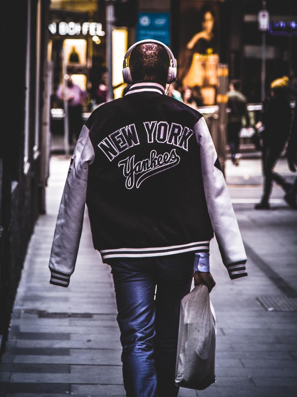 Free Image of Man Walking Down Street Holding Bag 