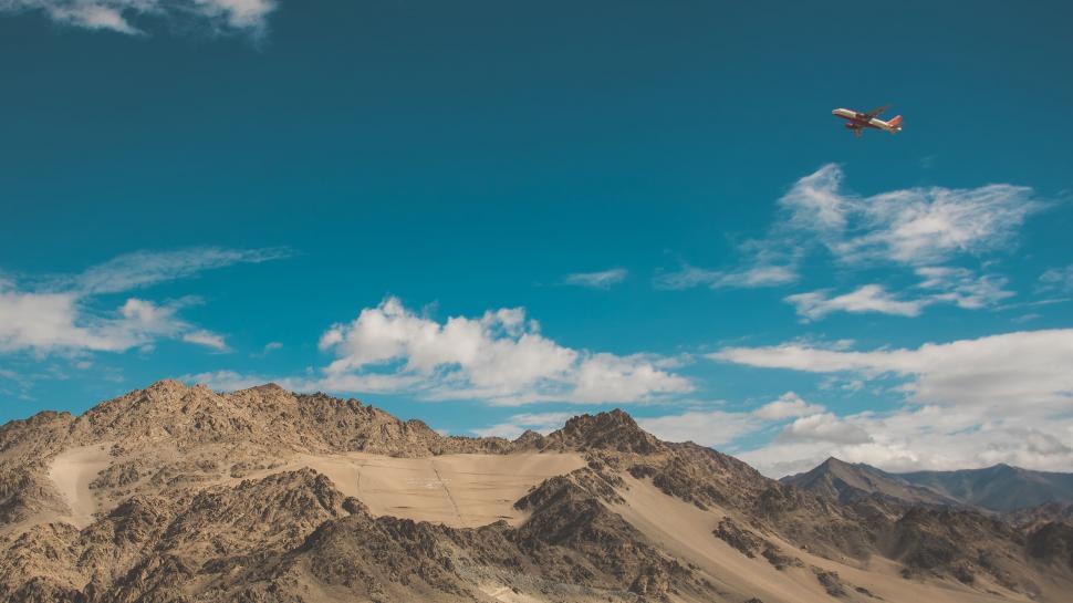 Free Image of Plane Flying Over Mountain Range in Blue Sky 