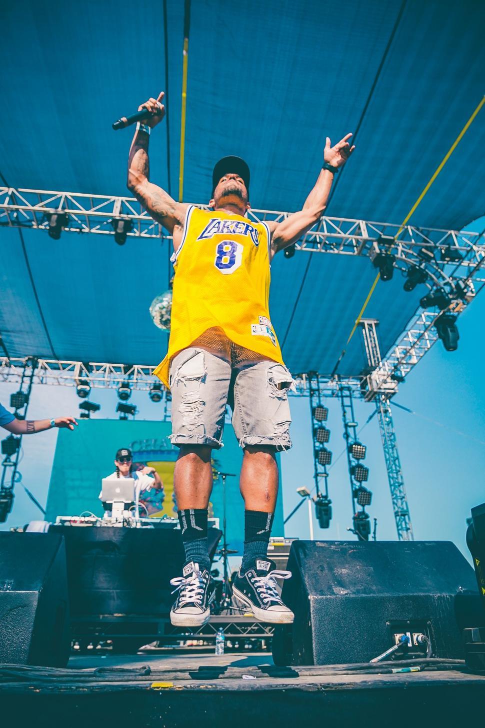 Free Image of Man Standing on Stage With Hands Raised 