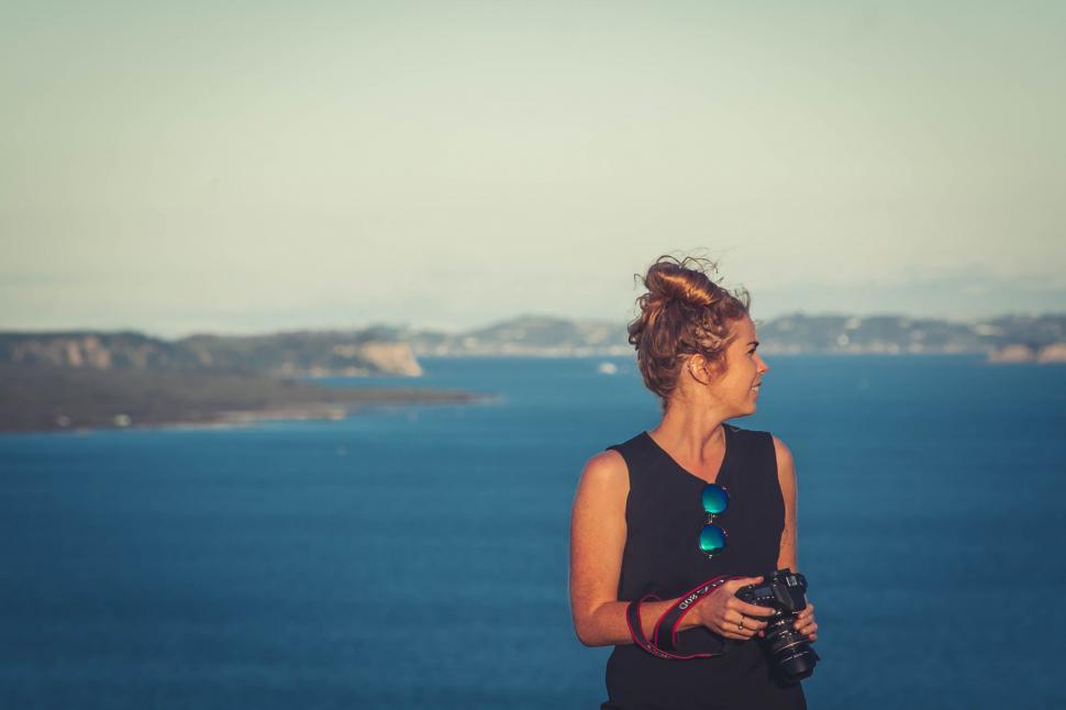Free Image of Woman Standing on Top of Hill by the Ocean 