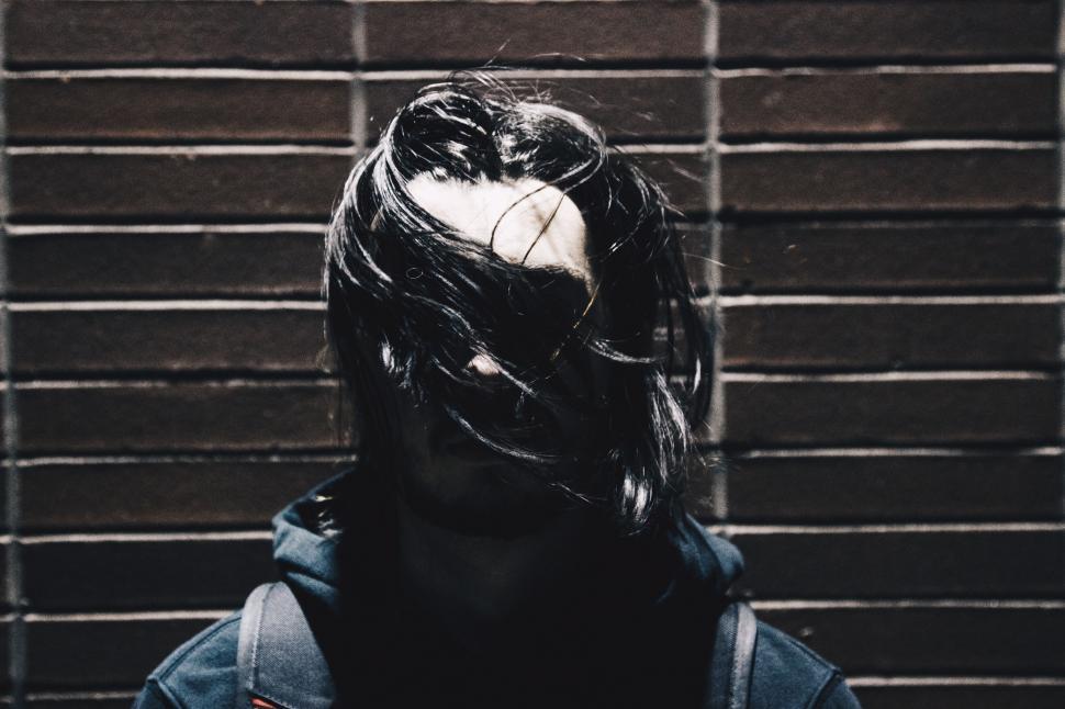 Free Image of Person With Long Hair Standing in Front of Brick Wall 