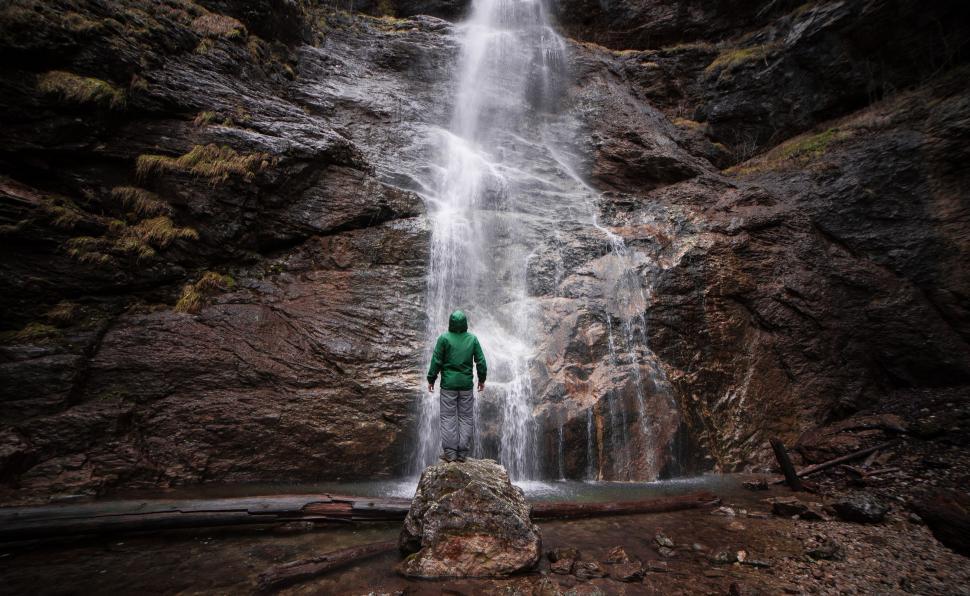 Free Image of Man Standing in Front of a Waterfall 