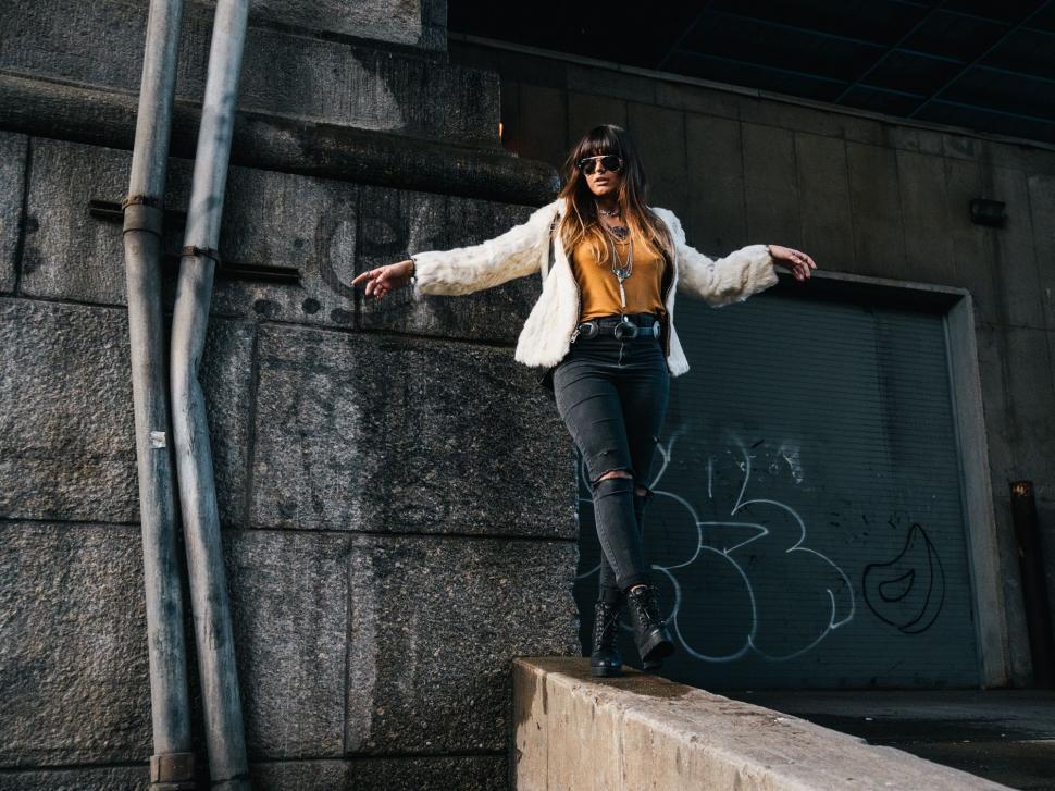 Free Image of Woman Standing on Top of Cement Wall 