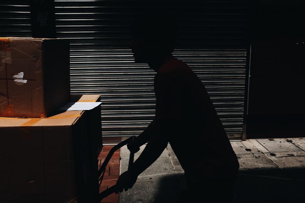 Free Image of Man Walking Next to Tall Box on Street 