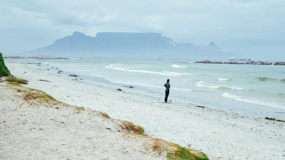 Free Image of Man Standing on Beach Next to Ocean 