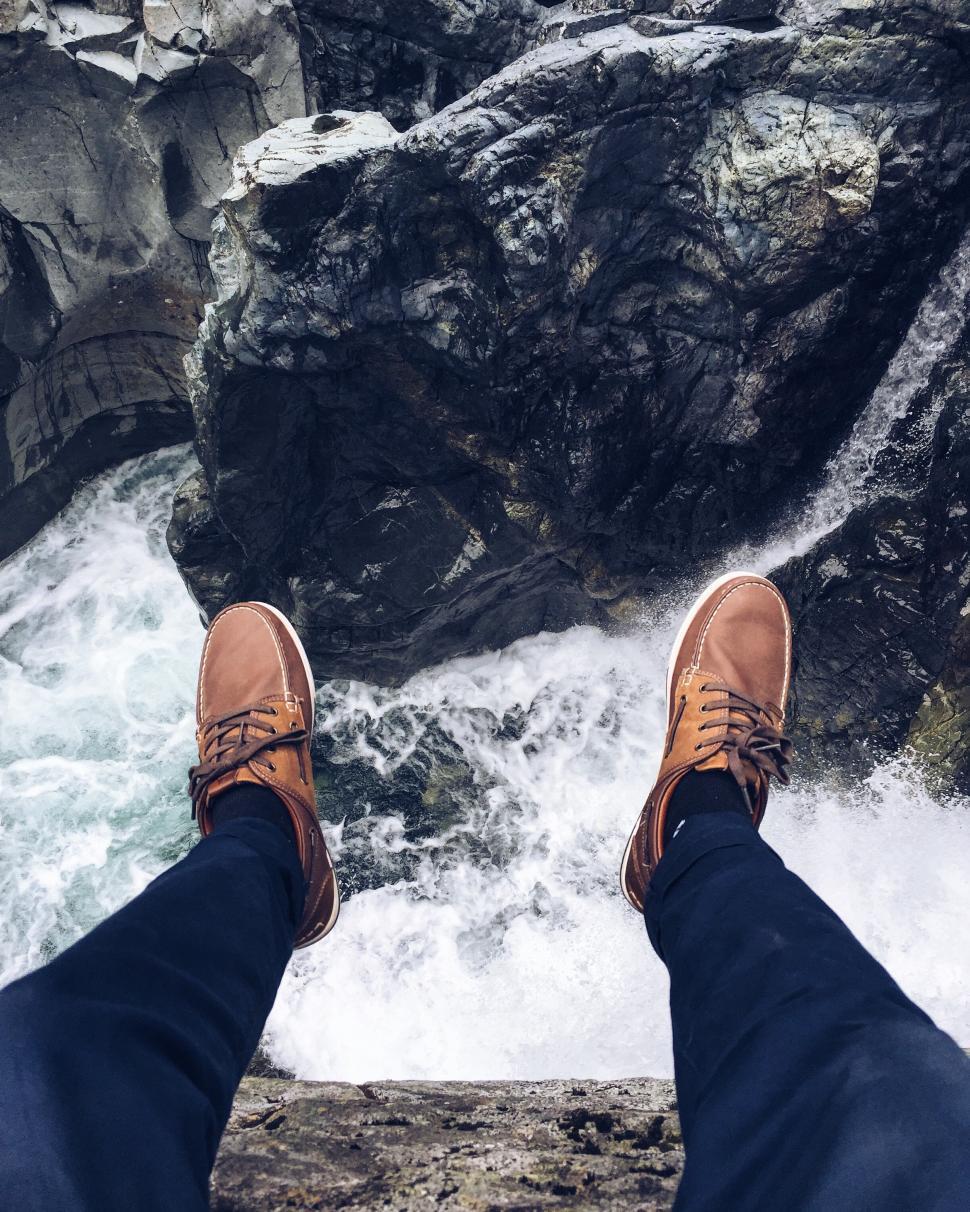 Free Image of Person Standing on Top of Rock by Water 