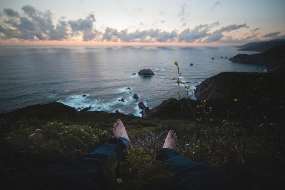 Free Image of Person Sitting on Hill Overlooking Ocean 