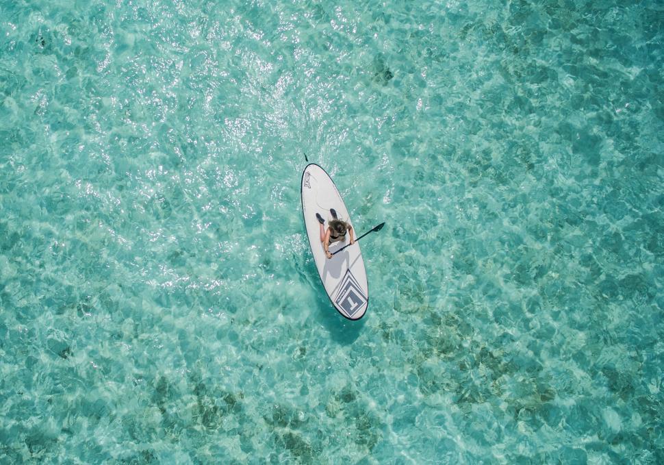 Free Image of Man Riding Paddle Board on Body of Water 
