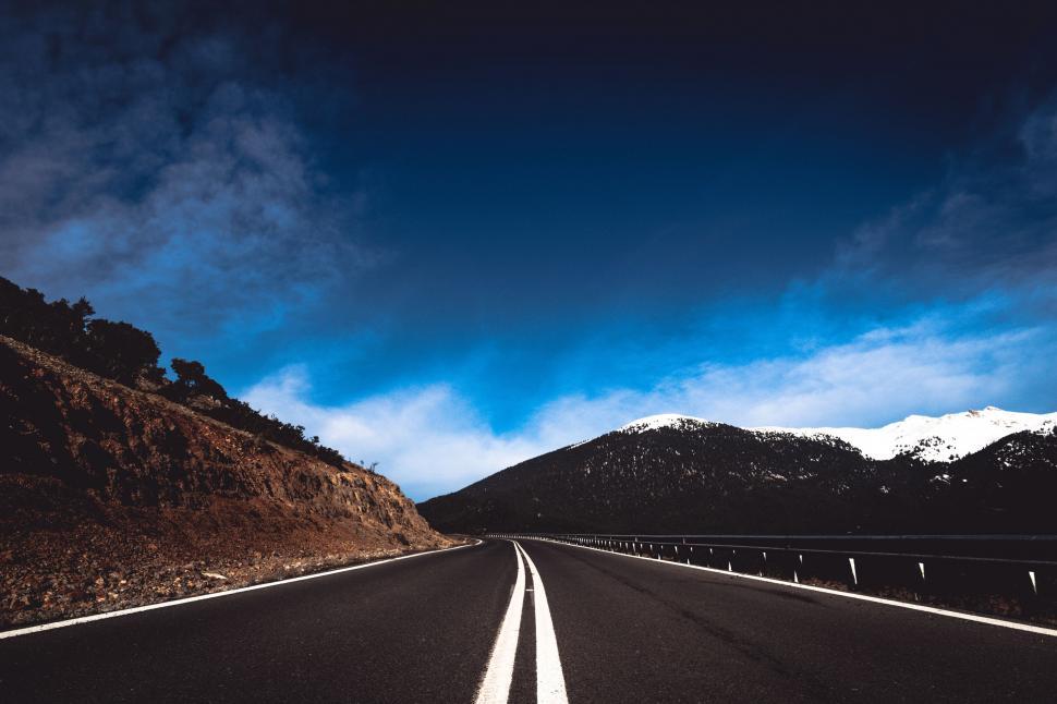 Free Image of A Quiet Road Surrounded by Mountains 