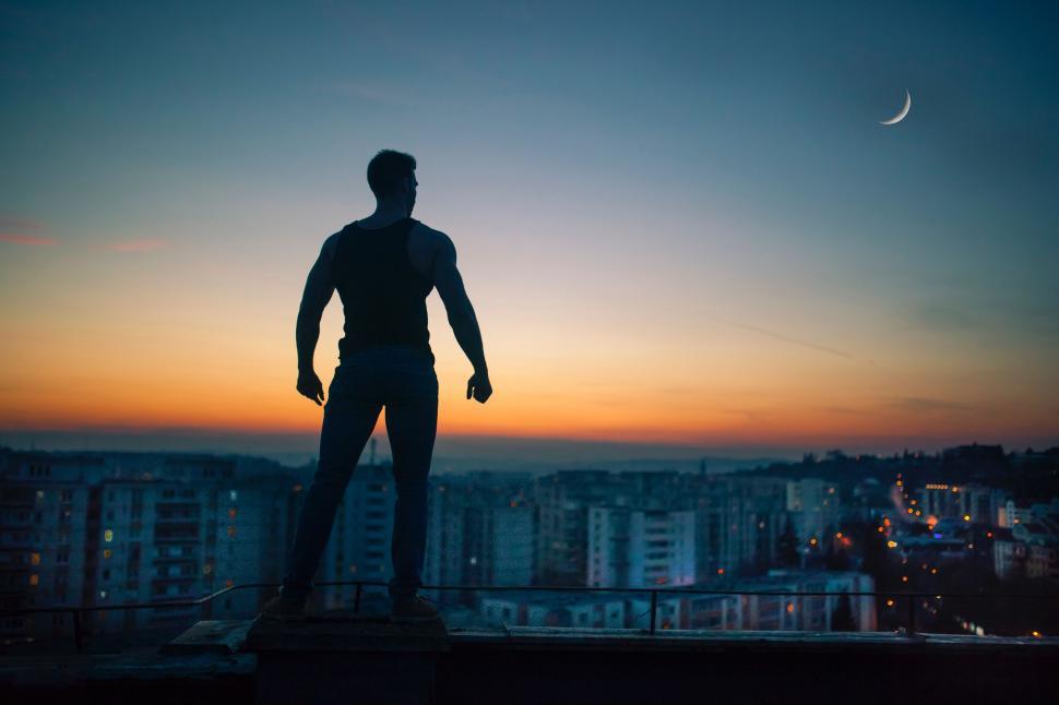Free Image of Man Standing on Roof Next to Tall Building 