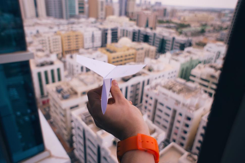 Free Image of Hand Holding Paper Airplane Over City 