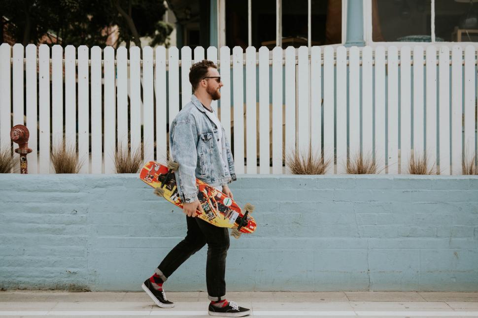 Free Image of Man Walking Down Street Holding Skateboard 