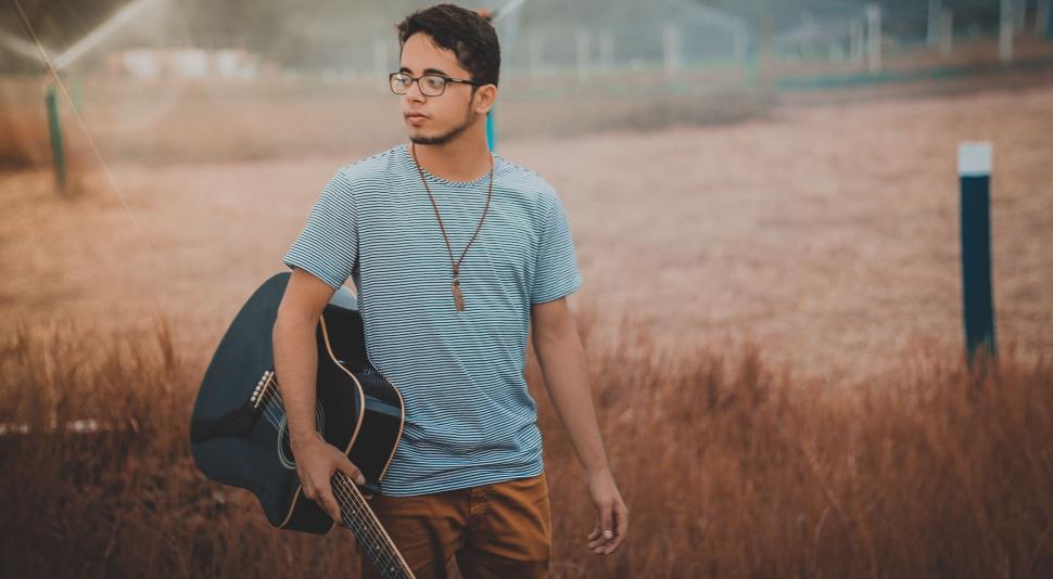 Free Image of Man Holding Guitar in Field 