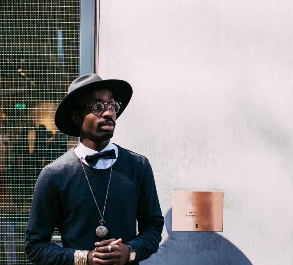 Free Image of Man Wearing Hat and Glasses Standing in Front of Window 