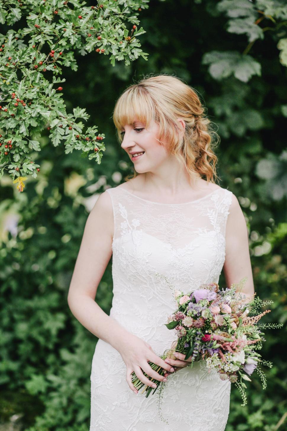 Free Image of Woman in Wedding Dress Holding Bouquet of Flowers 