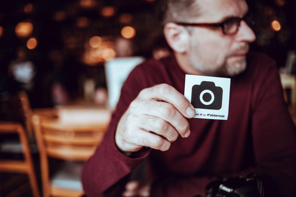 Free Image of Man Sitting at Table Holding Camera 