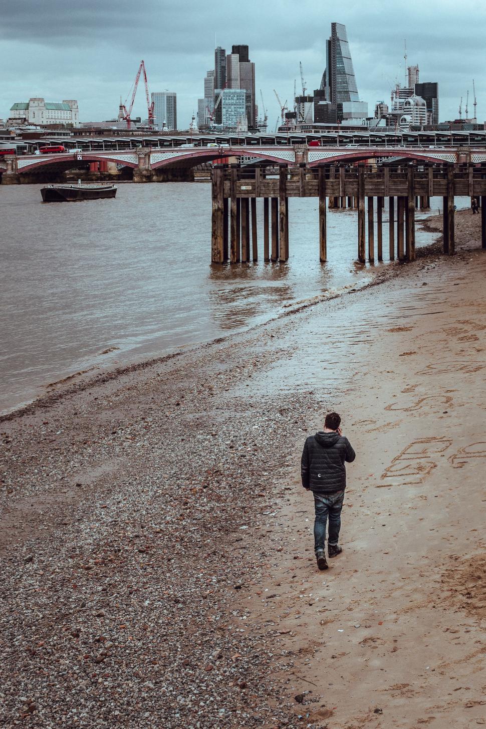 Free Image of Man Walking on Beach Along Water 