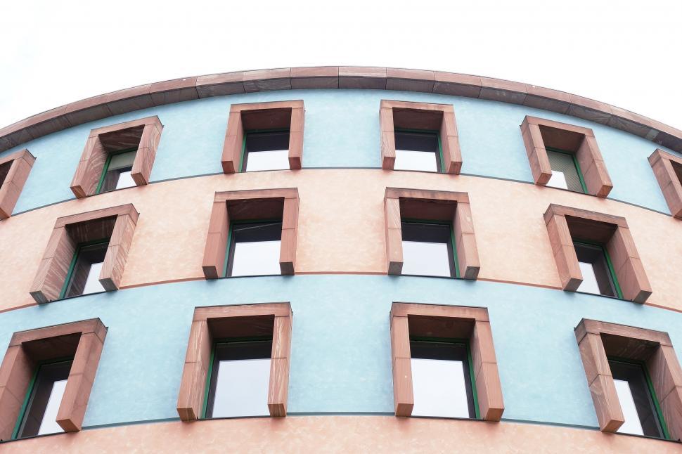 Free Image of Round Building With Many Windows Against Sky Background 