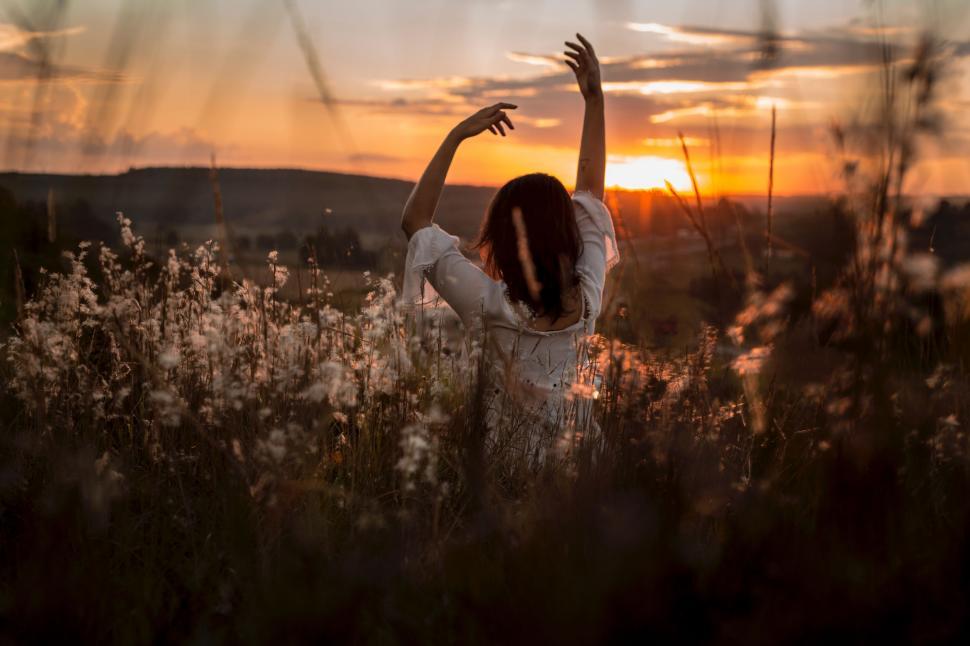 Free Image of Woman Standing in Field With Arms Raised 