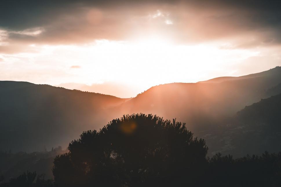 Free Image of Sun Shining Through Clouds Over Mountains 