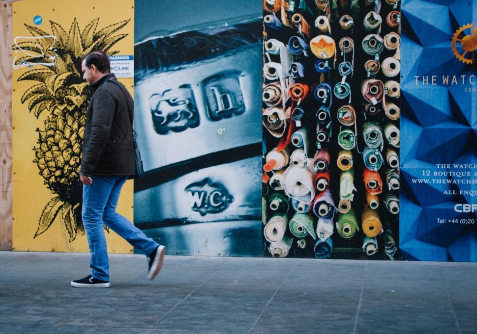 Free Image of Man Walking Down Sidewalk Next to Wall 