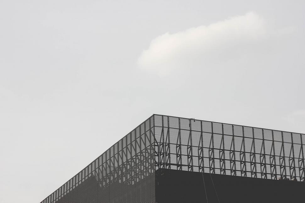 Free Image of Plane Flying Over Building With Sky Background 