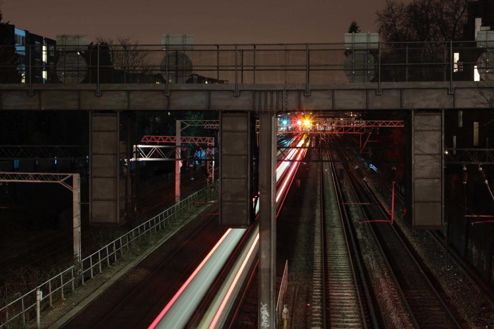 Free Image of Train Traveling Down Train Tracks Under Bridge 