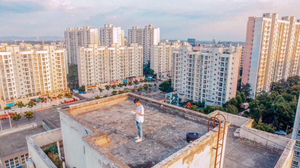 Free Image of Man Standing on Top of Building Next to Tall Buildings 