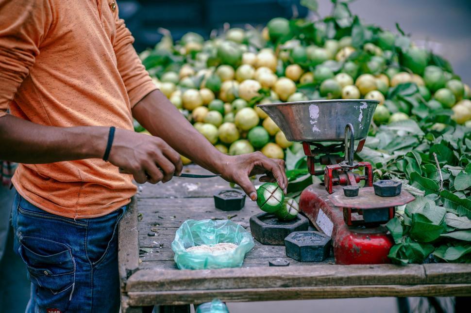 Free Image of Man Standing Next to Table Filled With Fruit 