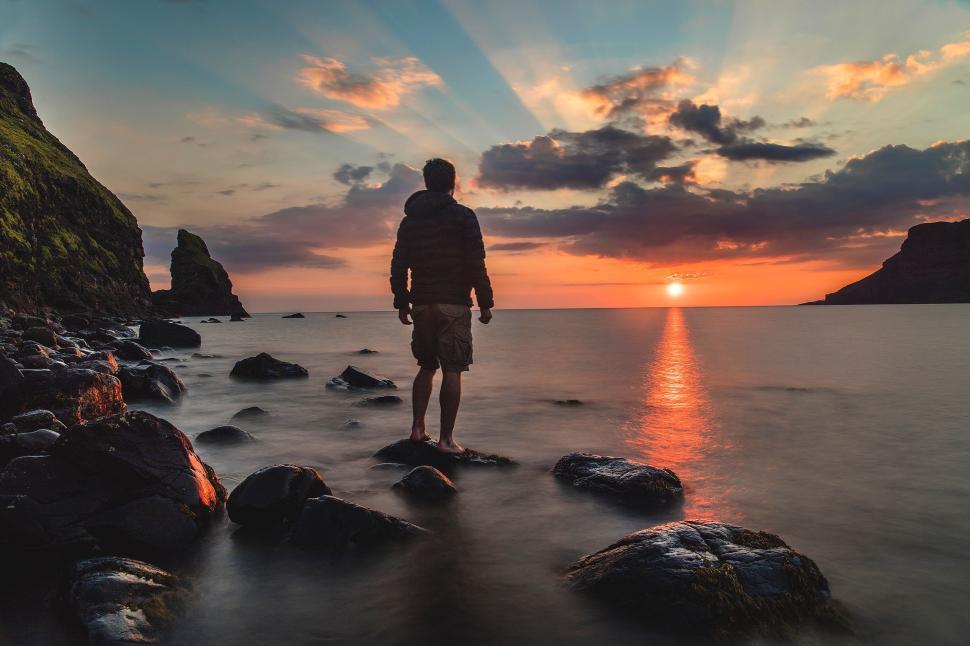 Free Image of Man Standing on Rocky Beach Next to Ocean 