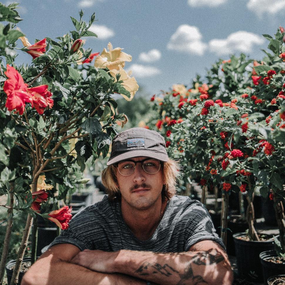 Free Image of Man With Hat and Glasses Sitting in Greenhouse 